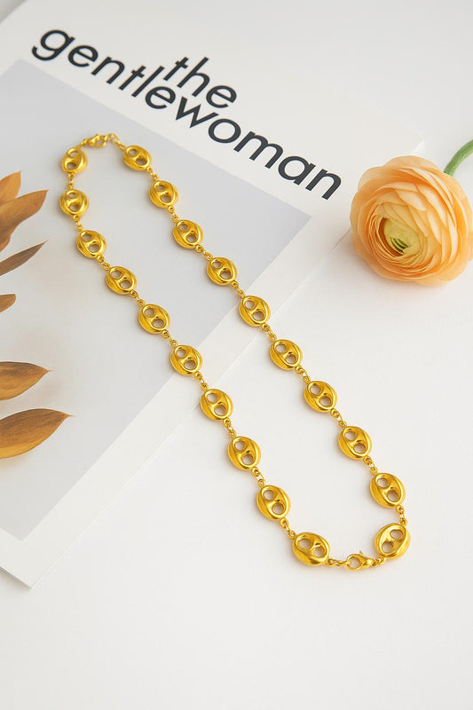 Minimalist Necklace in shiny gold-tone links laid on a magazine page next to a peach ranunculus flower, showcasing elegant 18K gold plated luxury accessories style.
