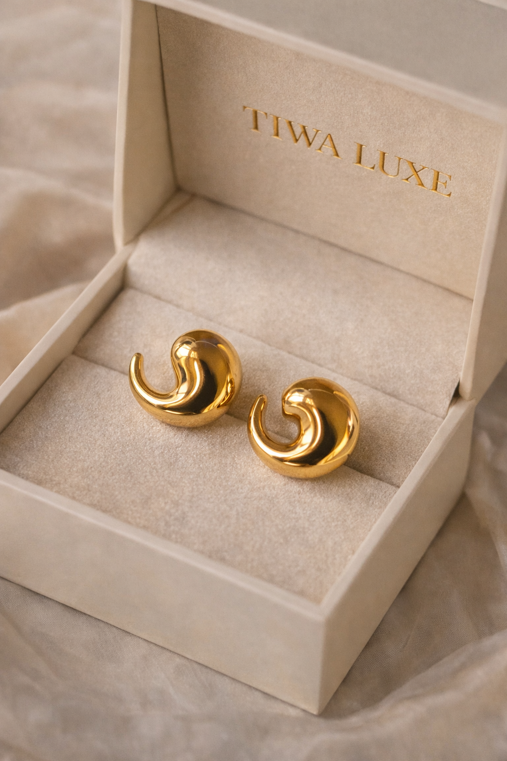 Bold Luxe Gold Stud Earrings displayed in a luxury beige velvet jewelry box with a smooth, polished swirl design, perfect for statement jewellery and gold jewellery collections.