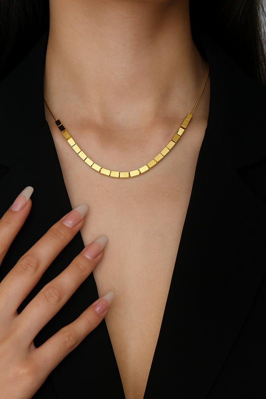 Close-up of a woman wearing a gold cube Cut Necklace with geometric square links, paired with a black outfit, showcasing elegant and modern luxury accessories.