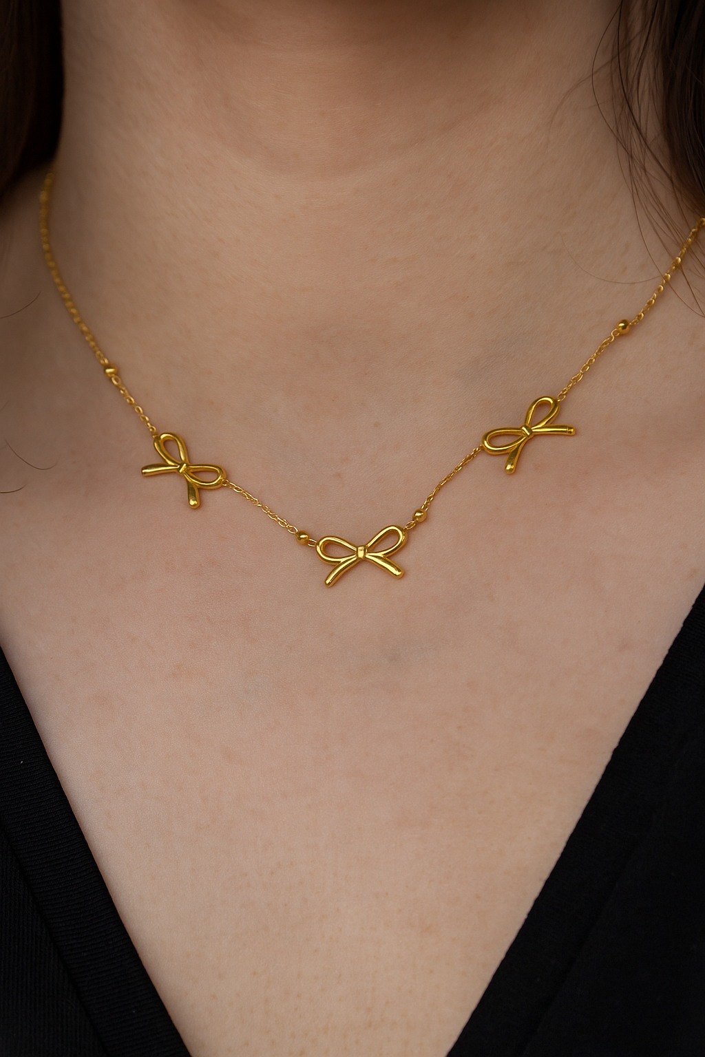 Close-up of a woman wearing a delicate Bow necklace set featuring three small gold bow charms on a fine gold chain, perfect for elegant everyday luxury accessories.