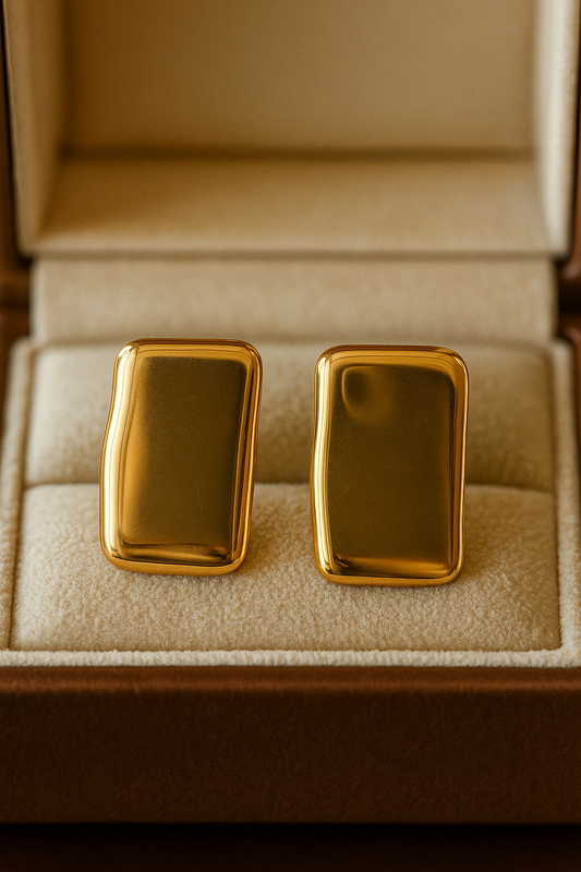 Pair of polished rectangular gold stud earrings displayed in a beige velvet jewelry box, highlighting the sleek and modern design of the luxe stud earring.