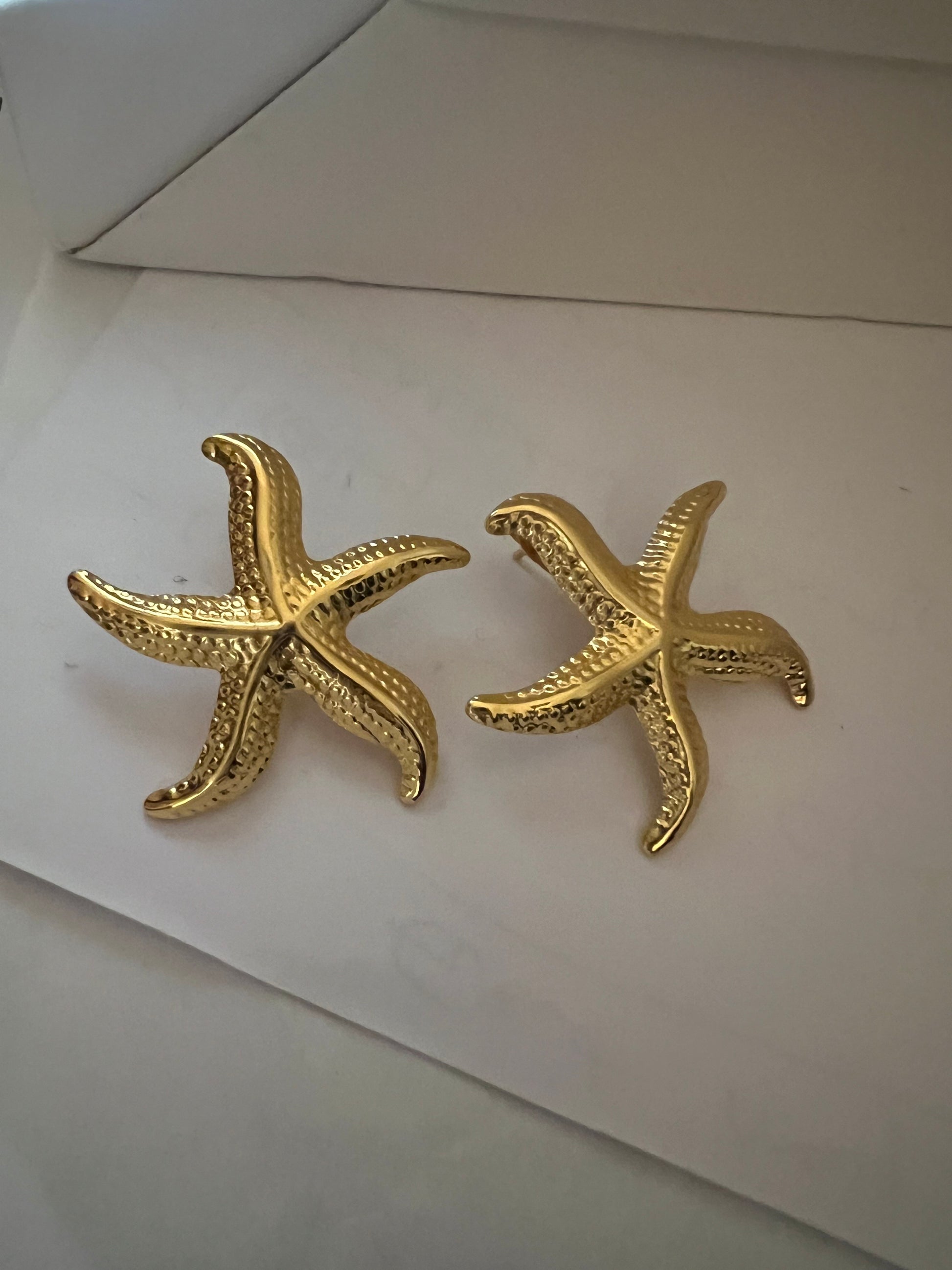 Pair of elegant gold star fish Earrings with intricate textured detailing, showcasing a luxurious and hypoallergenic design ideal for stylish, statement jewellery lovers.