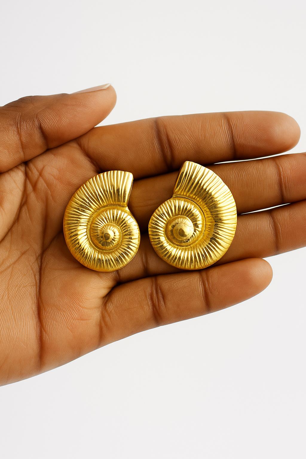 Hand holding a pair of spiral-shaped Elegant Hypoallergenic Earrings – 18K Gold Plated Stainless Steel with a textured, shiny gold finish.