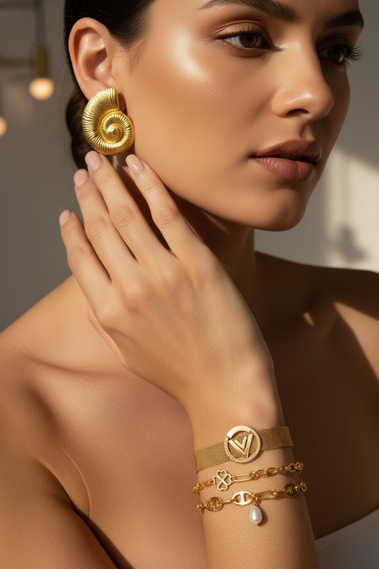 Close-up of a woman wearing Elegant Hypoallergenic Earrings – 18K Gold Plated Stainless Steel with textured spiral design, paired with stylish gold bracelets and a pearl charm.